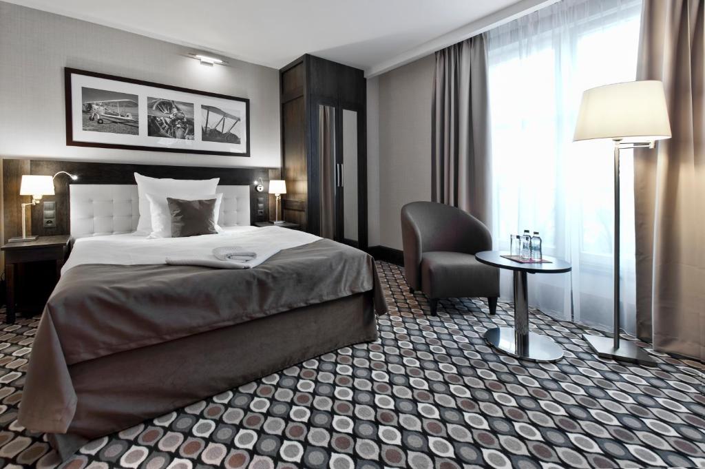 ein Hotelzimmer mit einem Bett und einem Stuhl in der Unterkunft Red Baron Hotel & Restaurant in Świdnica