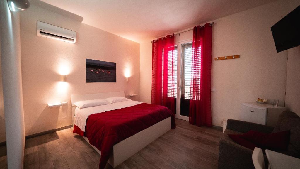a bedroom with a bed and a window with red curtains at Sirio Marsala in Birgi Vecchi