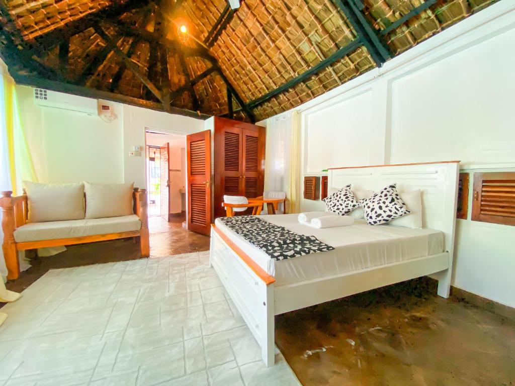 a bedroom with a bed and a chair in it at Palm Villa at Villa Sol in Mombasa
