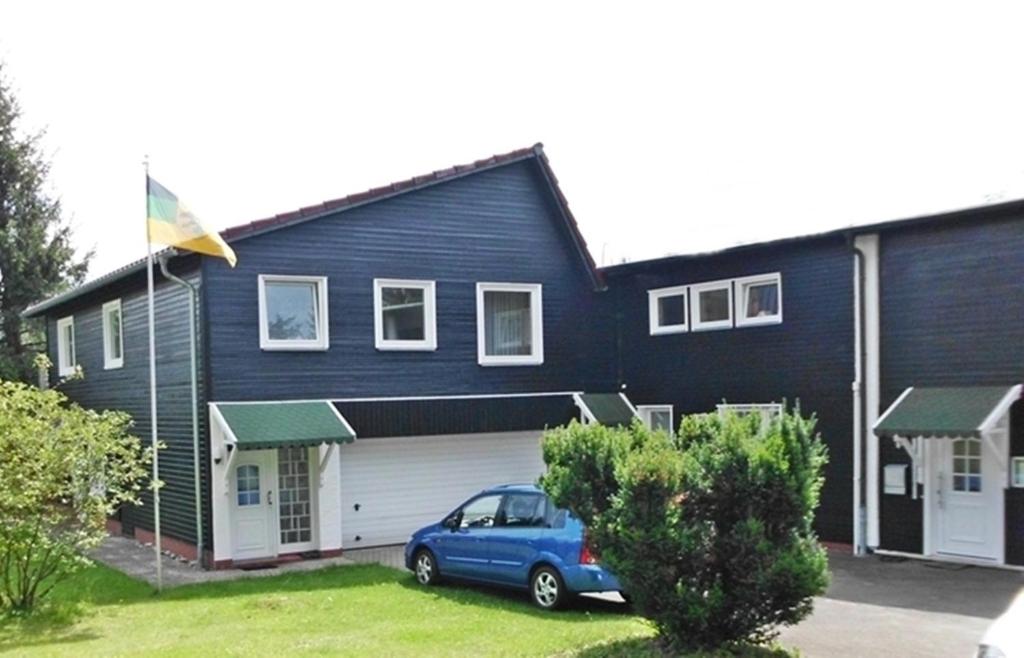 a blue car parked in front of a black house at Premium-Ferienwohnungen Bergblick im Haus Hopfe in Hahnenklee-Bockswiese