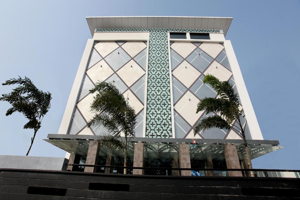 a tall building with palm trees in front of it at Paradigm Sarovar Portico in Kākināda