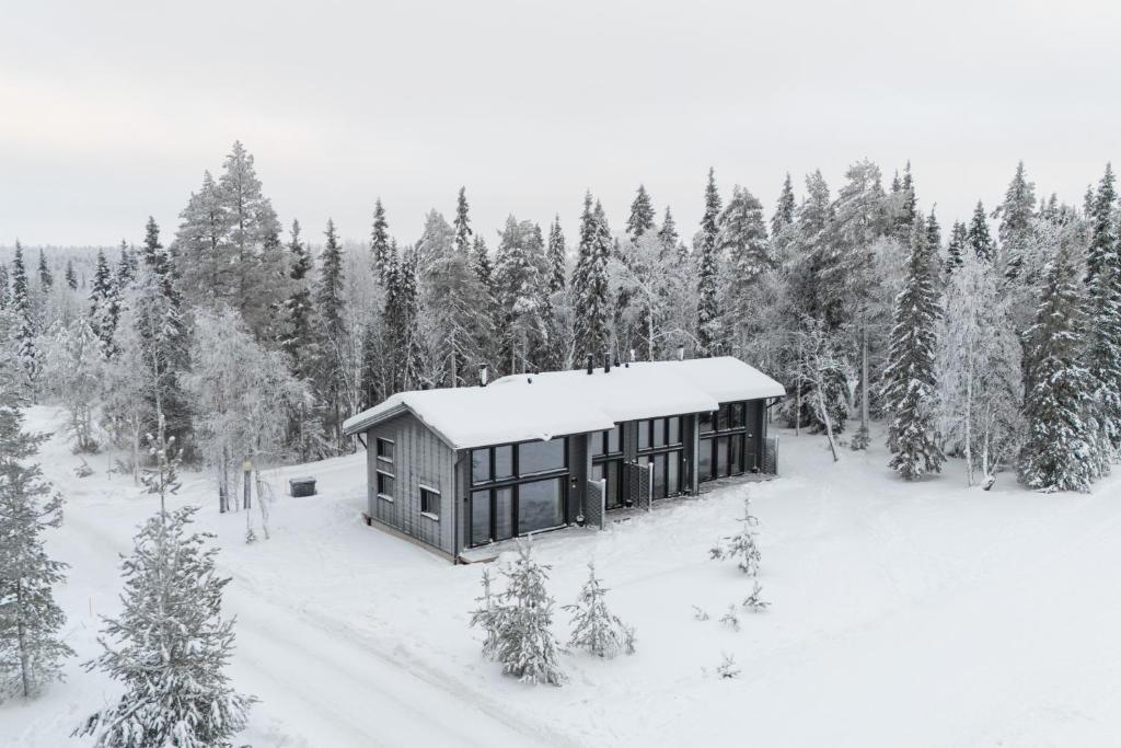 a cabin in the middle of a snow covered forest at Deluxe Luosto in Luosto