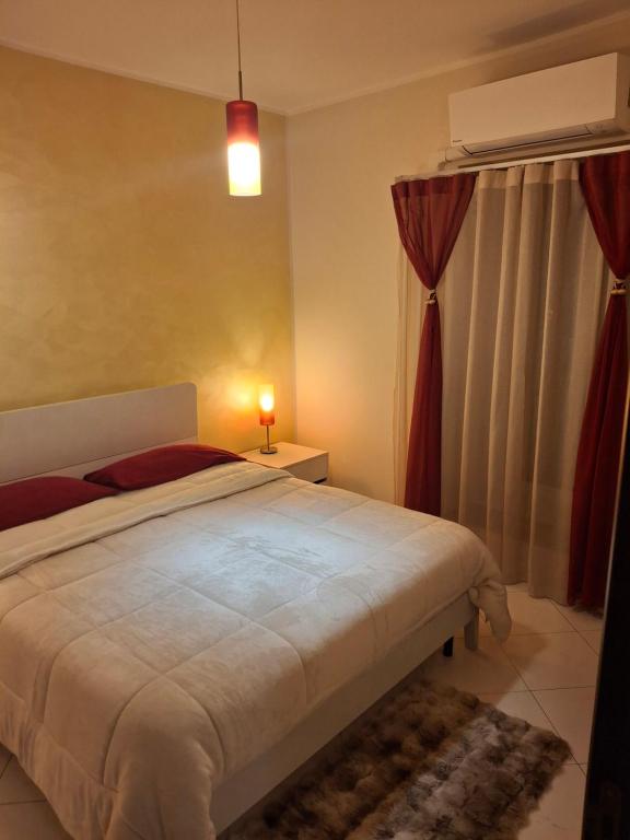 a bedroom with a large white bed with red curtains at Soleil in Nicosia