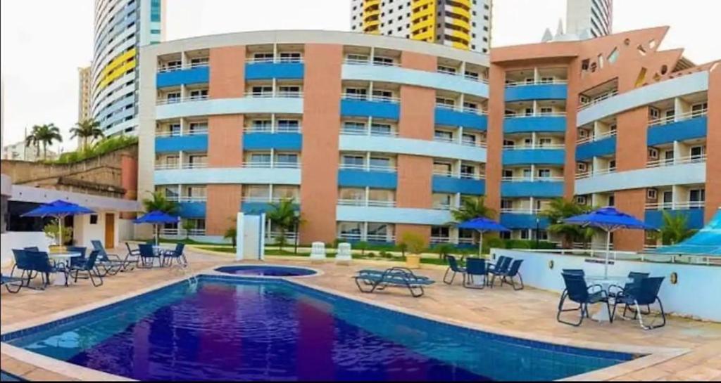 a hotel with a pool and chairs and a building at Flat no Terrazzo perto do mar in Natal