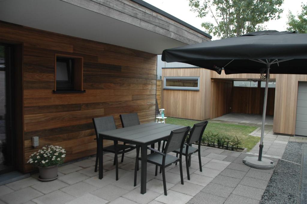 a patio with a table and chairs and an umbrella at Vakantiewoning Duinviooltje-Koksijde in Koksijde