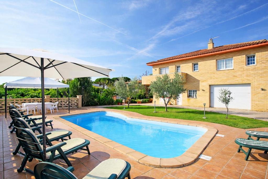 a swimming pool with chairs and an umbrella and a house at Catalunya Casas Tranquil Costa Brava Retreat with private suite! in Sils