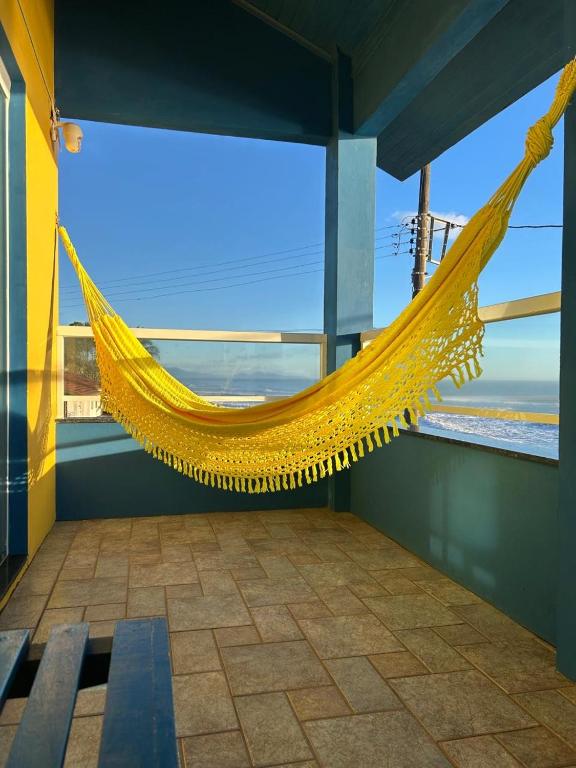 a yellow hammock in a room with a view of the ocean at Pé na areia apto Rassy in Itapoa