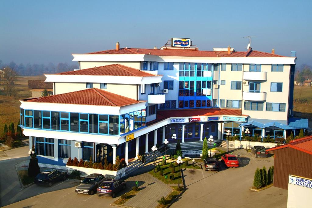 a large white building with cars parked in a parking lot at Hotel Split in Usora