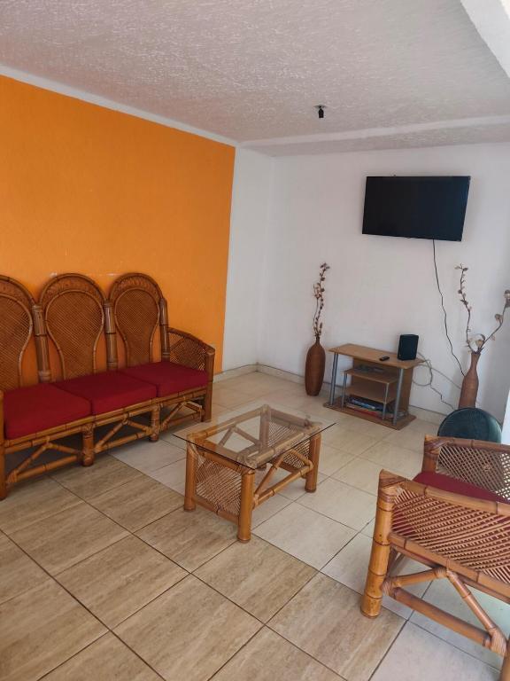 a living room with couches and a tv on a wall at Casa Ixtapa in Ixtapa