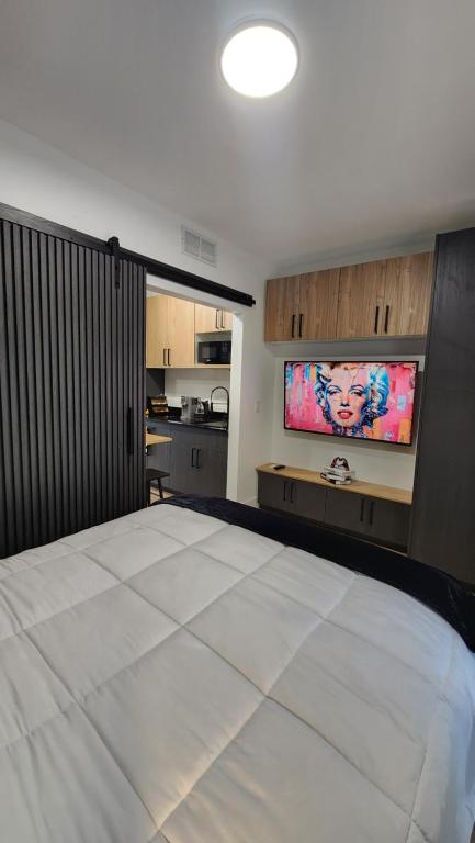 a bedroom with a large white bed and a flat screen tv at Pop Art Loft in Hialeah