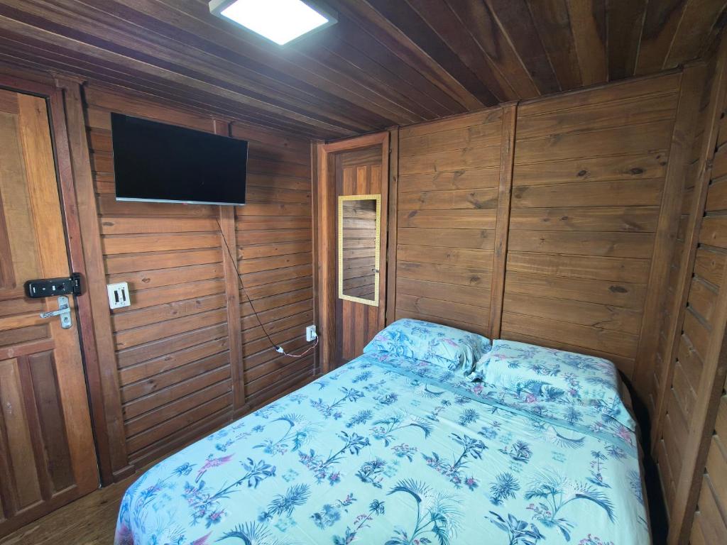 a small bedroom with a bed and a television at Oka do Mar Hospedaria - Suíte com varanda na Ilha do Mel - Nova Brasília in Ilha do Mel