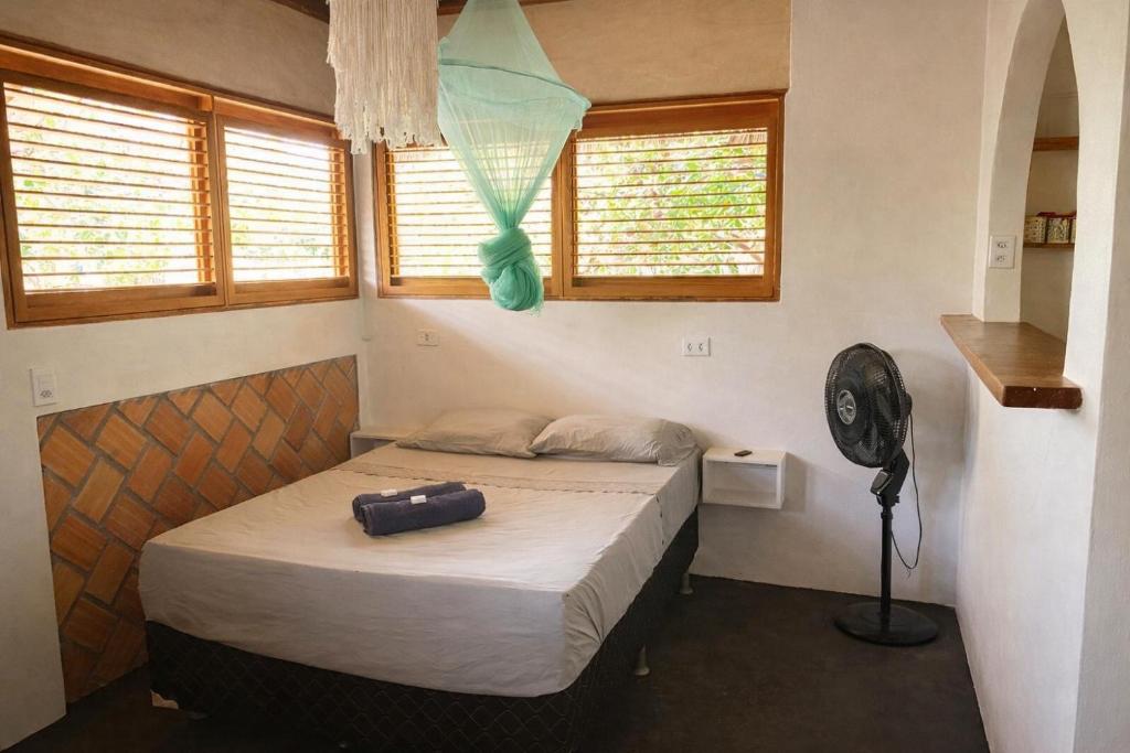 a small bedroom with a bed and a fan at Plancton House Atins in Atins