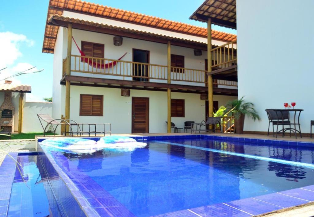 a villa with a swimming pool in front of a house at pousada mar e vento in Touros