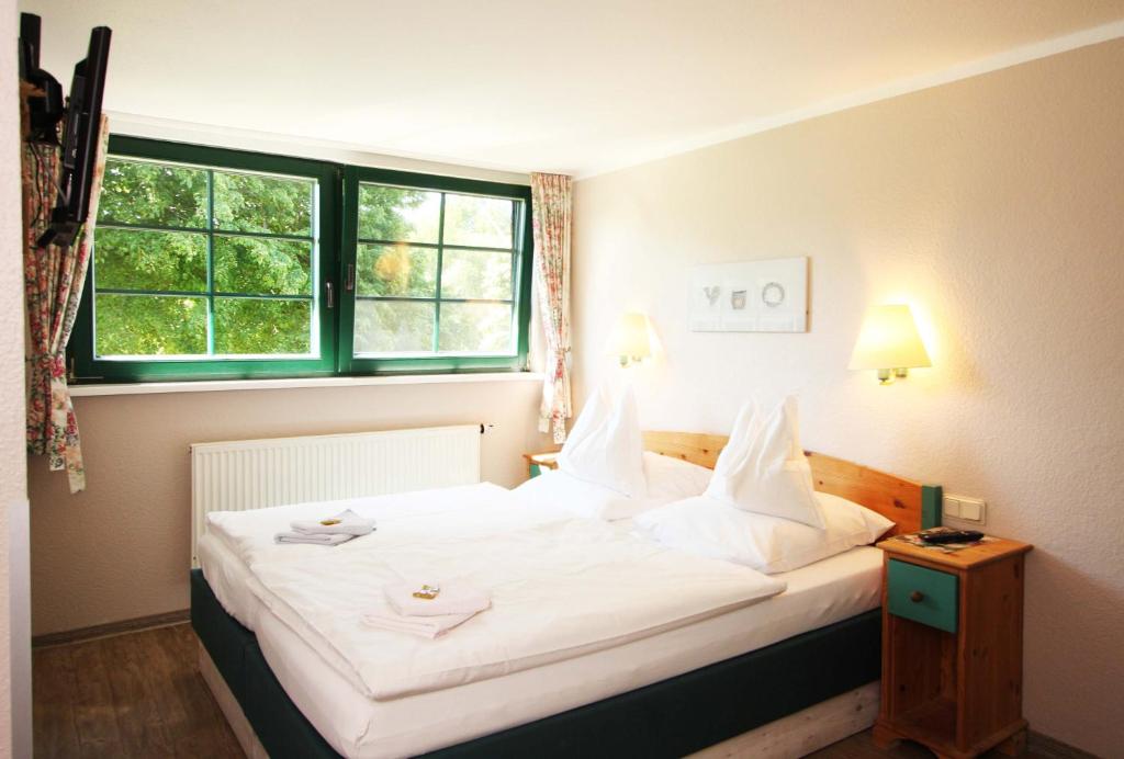 a bedroom with a large white bed with a window at Pension Forstfuhrmannshof in Markgrafenheide