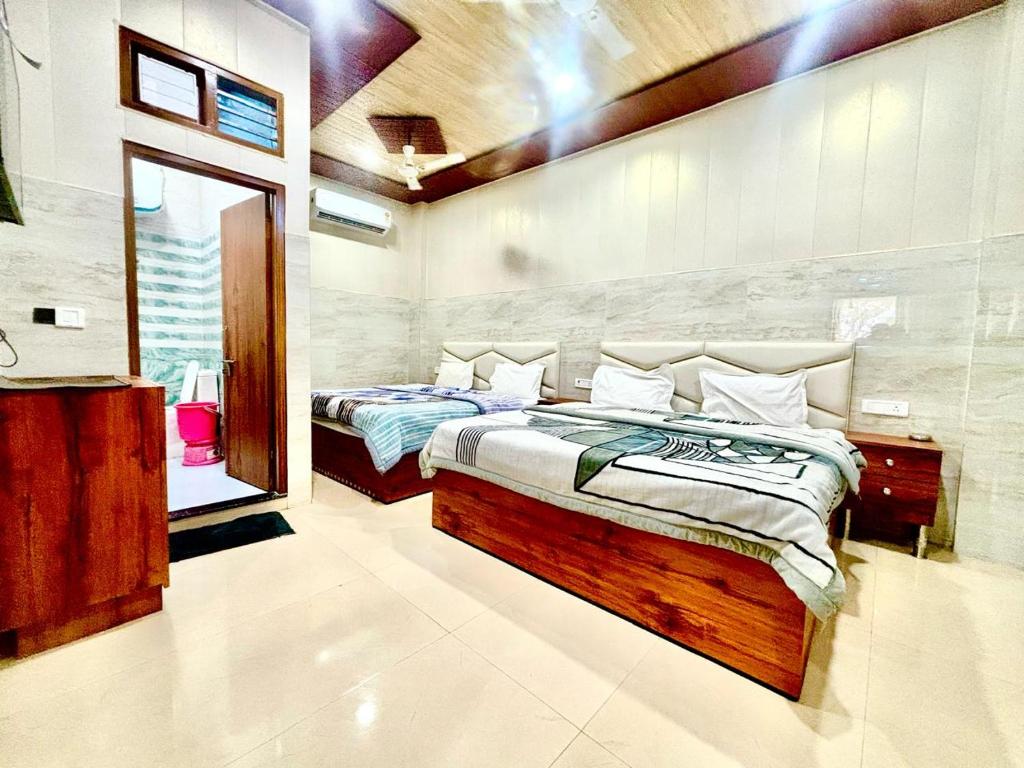 a bedroom with two beds and a mirror at Shri Murli Manohar Dham Hotel Vrindavan in Chhatikara