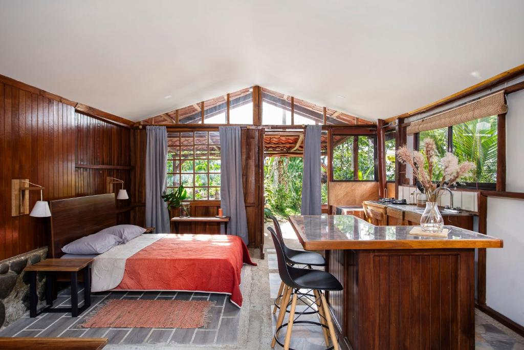 a bedroom with a bed and a desk and a kitchen at Casa Cúrcuma in Turrialba