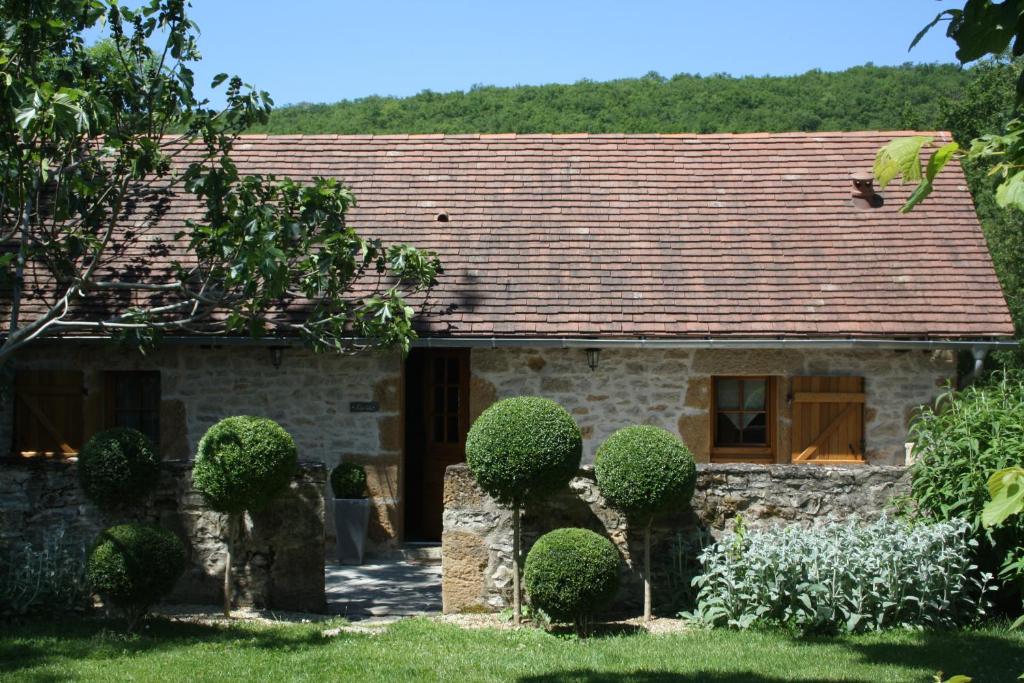 a stone house with a roof with bushes in front at Studio Natur'ailes, Le Hameau du Quercy, romantique, campagne, piscine naturelle in Frontenac