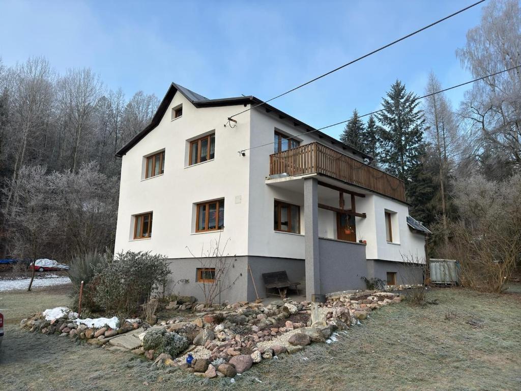 a white house with a balcony on top of it at Přijďte pobejt in Benecko