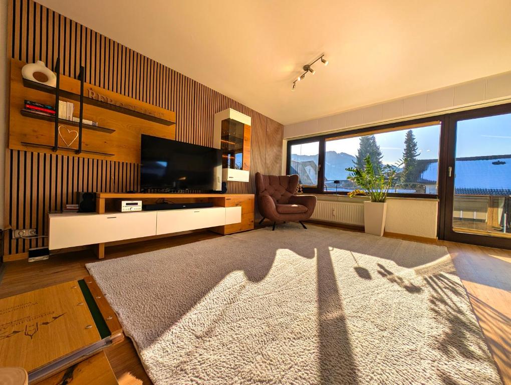 a living room with a flat screen tv and a chair at Ferienwohnung Alpenglut in Nesselwang