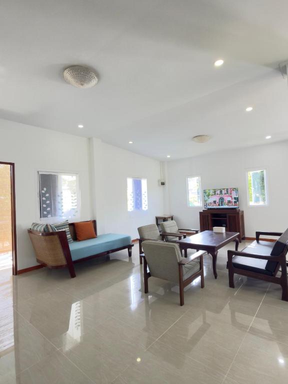 a waiting room with chairs and tables and windows at Baan Lanta in Ko Po