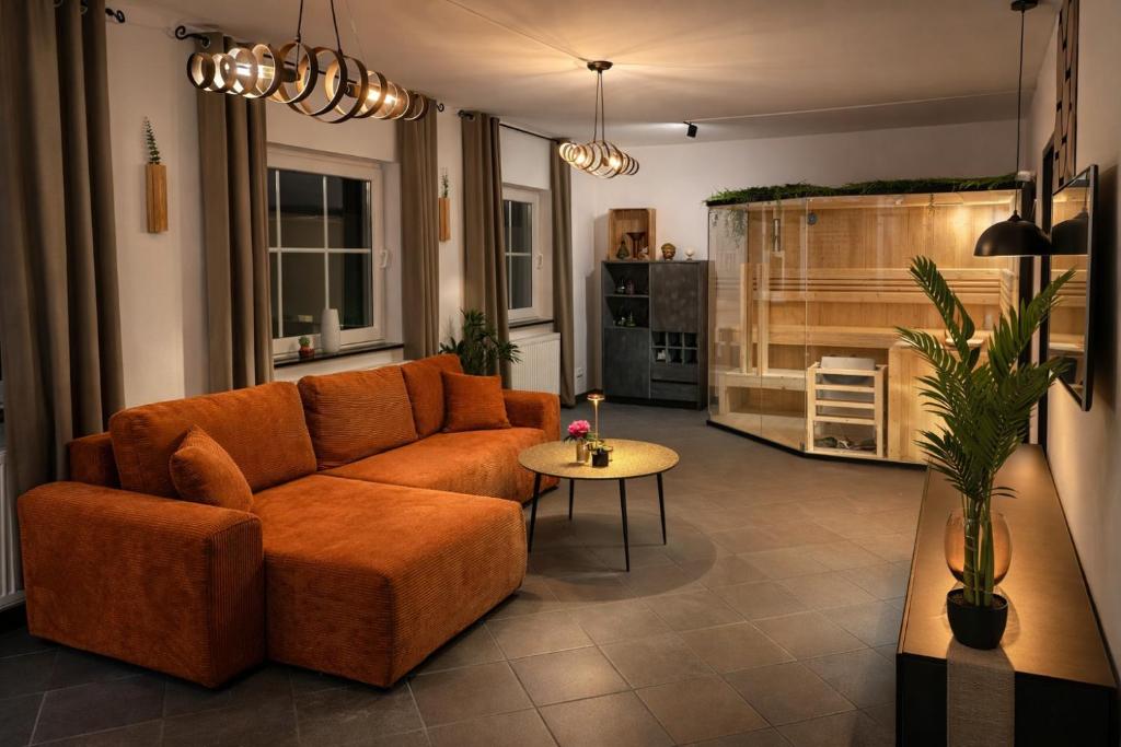 a living room with an orange couch and a table at Wellnesshaus - Whirlpool - Sauna - Relax in Herten