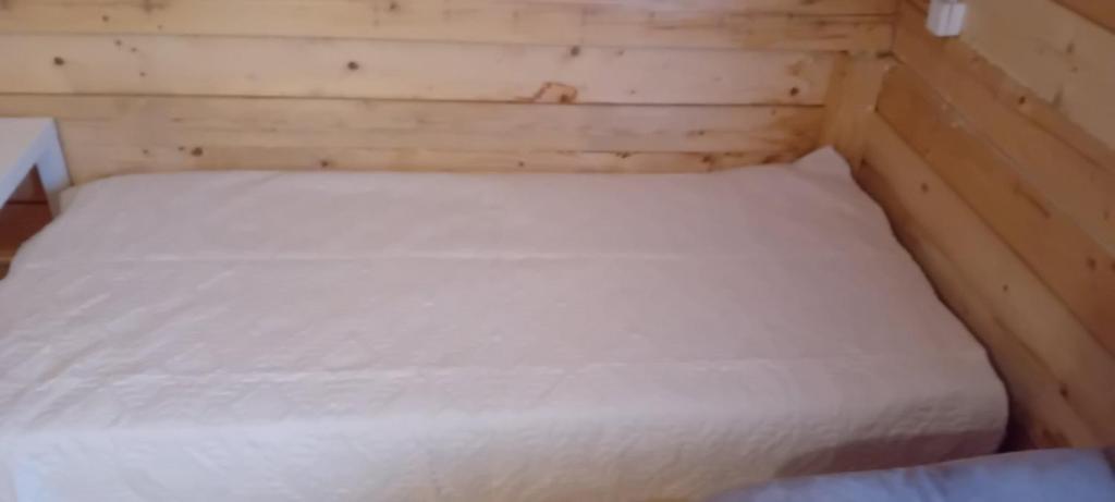 a small bed in a wooden room with white sheets at Vikendica strane in Mateševo
