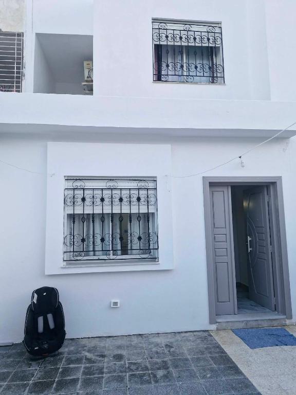 a white building with two windows and a door at Villa résidence privé Ariana in Ariana