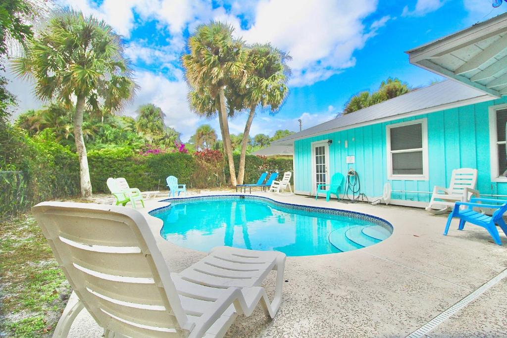 a blue house with a swimming pool and two lawn chairs at Pelican Cottage in Jensen Beach