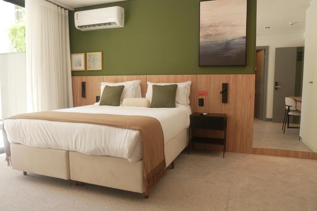 a bedroom with a large bed and a green wall at Xtay Oslo Florianópolis - Residential studio 5 minutes from downtown, close to Epic School and Atlantis Executive Center in Florianópolis