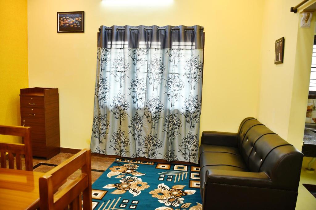 a living room with a couch and a curtain at Srinivasam service apartment in Madurai