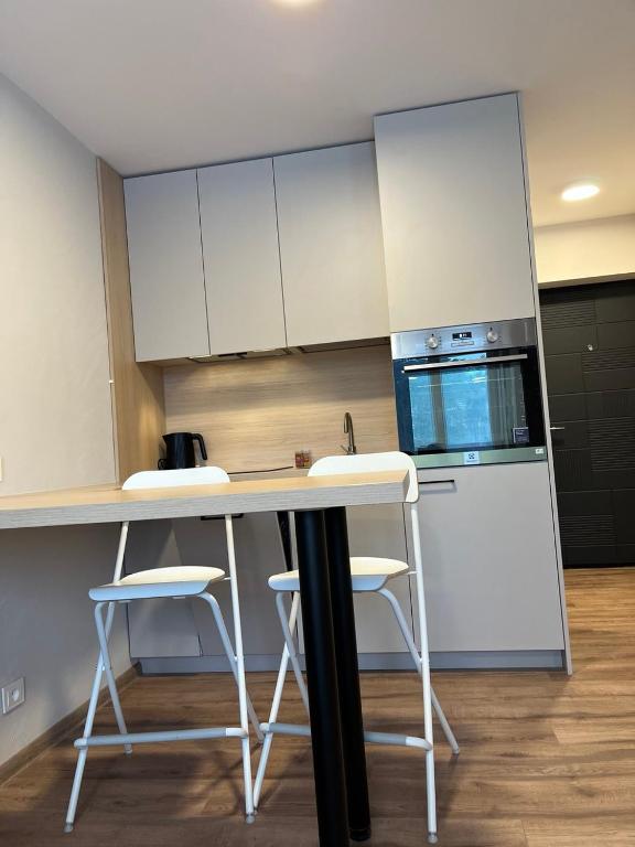 a kitchen with white cabinets and a counter with stools at Гнёздышко in Visaginas