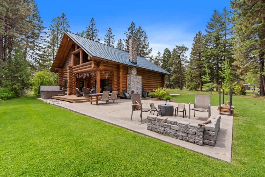 a log cabin with a patio and chairs in the grass at Big Jim Mountain Lodge - Pacific Retreats in Leavenworth