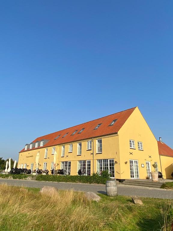 a large yellow building with a red roof at Gammel Løgten Strandkro in Hornslet