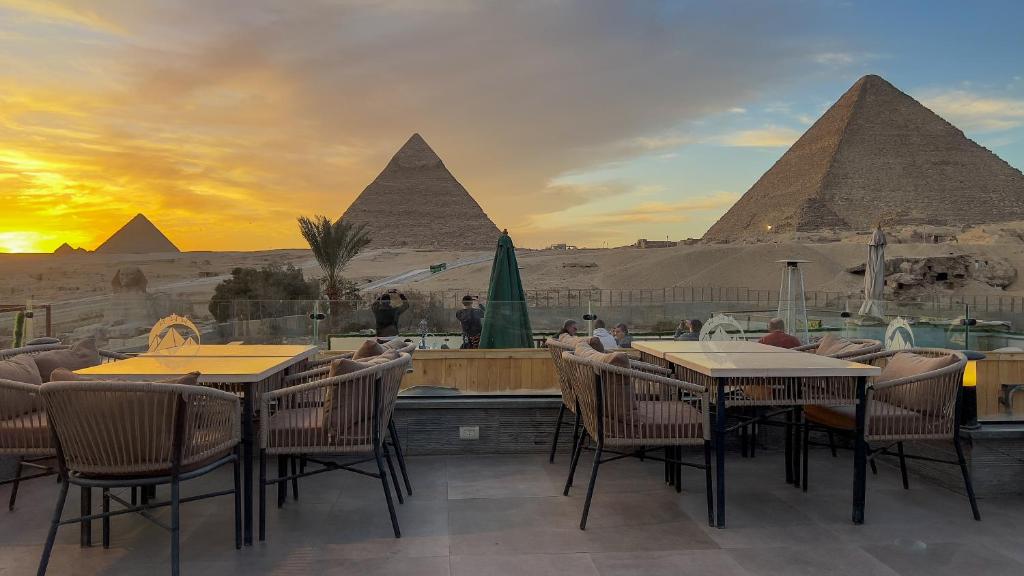 a restaurant with tables and chairs and the pyramids at Pyramids Height Luxury Wing in Cairo