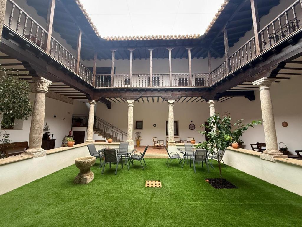 an indoor patio with chairs and a green lawn at La Casa de la botica -Casa Rural El Romeral de Toledo in Romeral