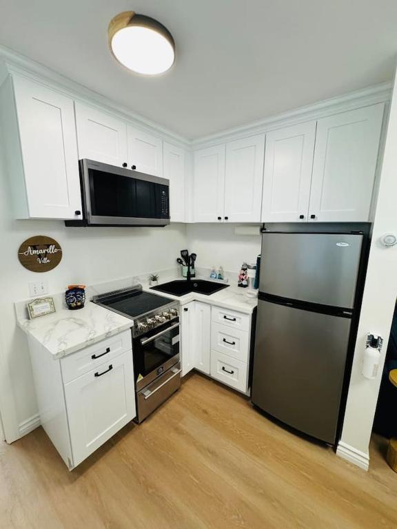 a kitchen with white cabinets and a stainless steel refrigerator at Cozy Villa with Spa, Fireplace, Kitchen, Yard, BBQ in Simi Valley