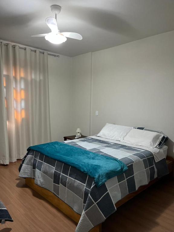 a bed in a bedroom with a ceiling fan at Hospedagem Casa de Déo in Domingos Martins