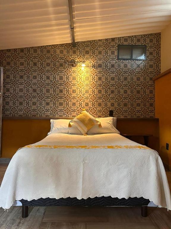 a bedroom with a white bed with a wall at El Bungalow de Juana in Tepoztlán