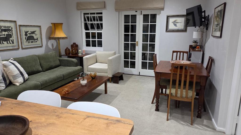 a living room with a green couch and a table at Hillcrest Cottage in Constantia