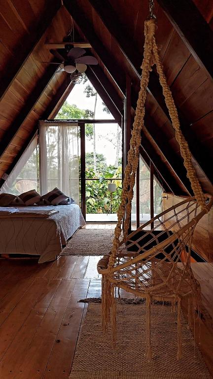 a room with a bed and a hammock in a attic at Cabañas Toku Laka in Fortuna