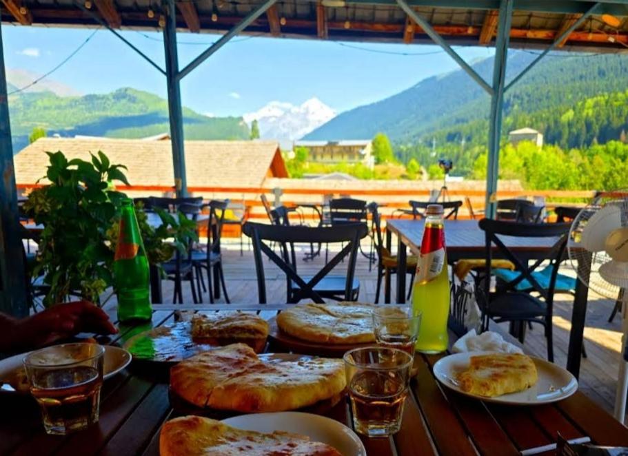 a wooden table with plates of food and drinks on it at Dodo Japaridze Guesthouse in Mestia