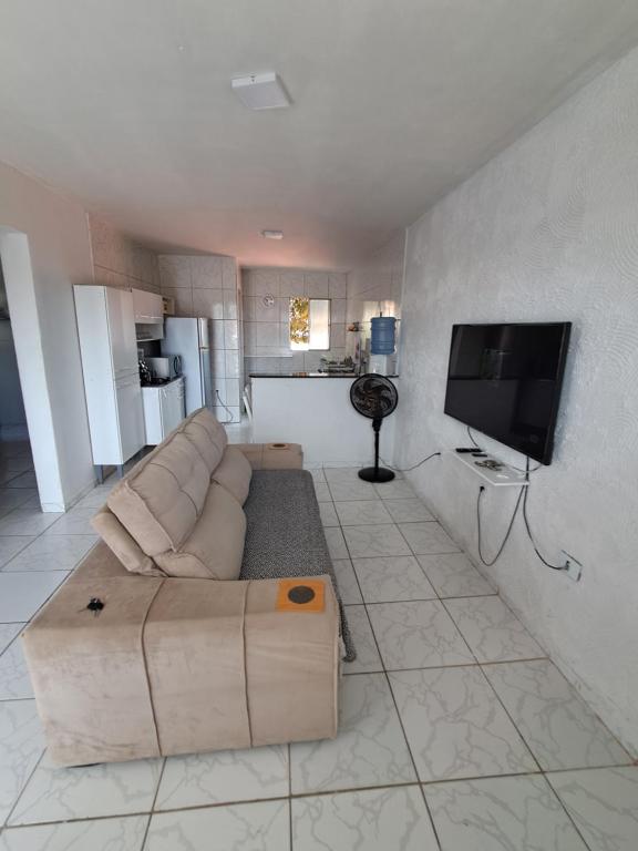 a living room with a couch and a flat screen tv at Apartamento Ryso do Mar Porto de Galinhas in Porto De Galinhas