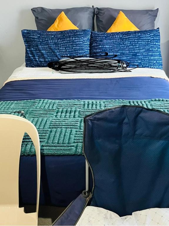 a bed with blue sheets and colorful pillows on it at Kasi Retreat in Northam