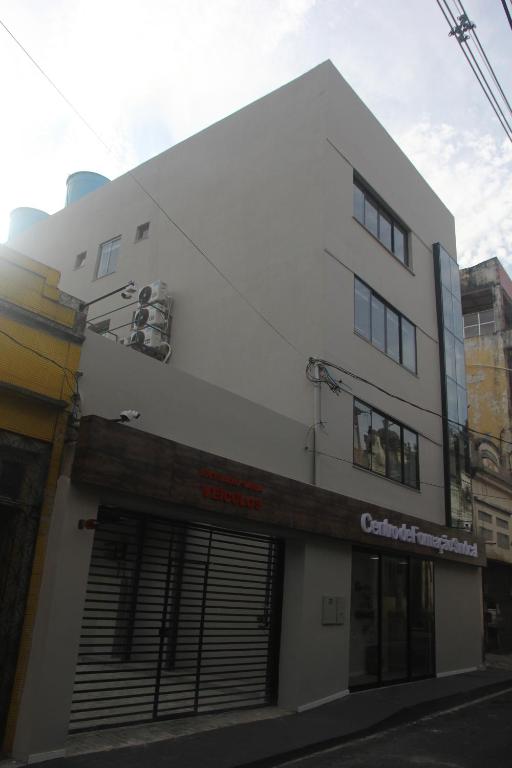 a white building with a garage on a street at Centro de Formação in Belém