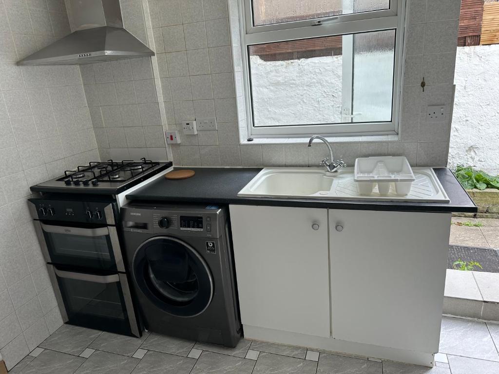 a kitchen with a washing machine and a sink at 4-Bed House in Enfield- Sleeps 8- Private garden in Enfield