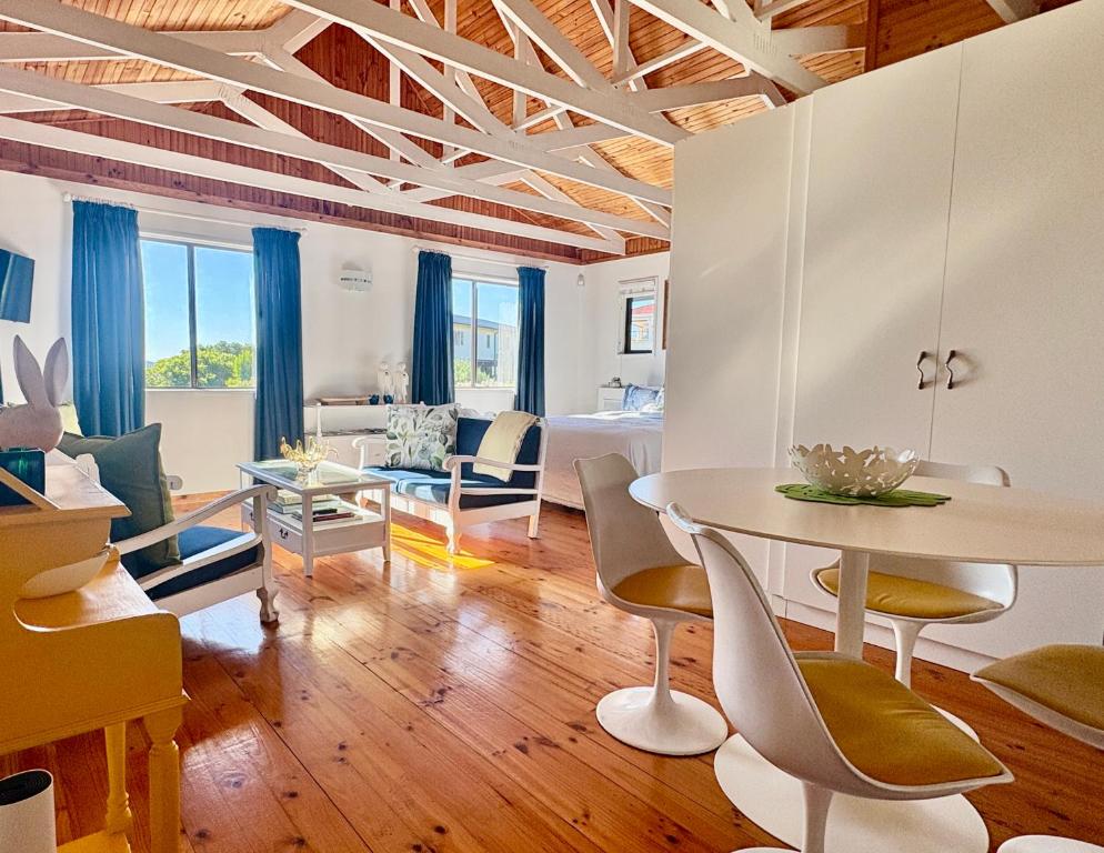 a dining room and living room with a table and chairs at Sunny studio in the sky in Brenton-on-Sea