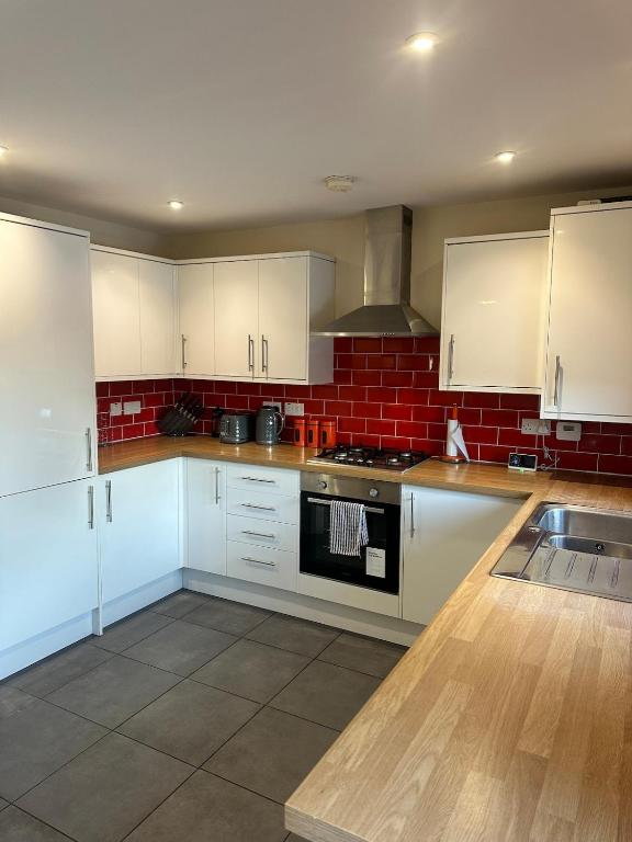 a kitchen with white cabinets and a stove top oven at Mill House in West Bromwich