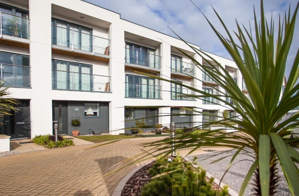 a white building with a palm tree in front of it at BEACHES - South Sands beach house in Torquay