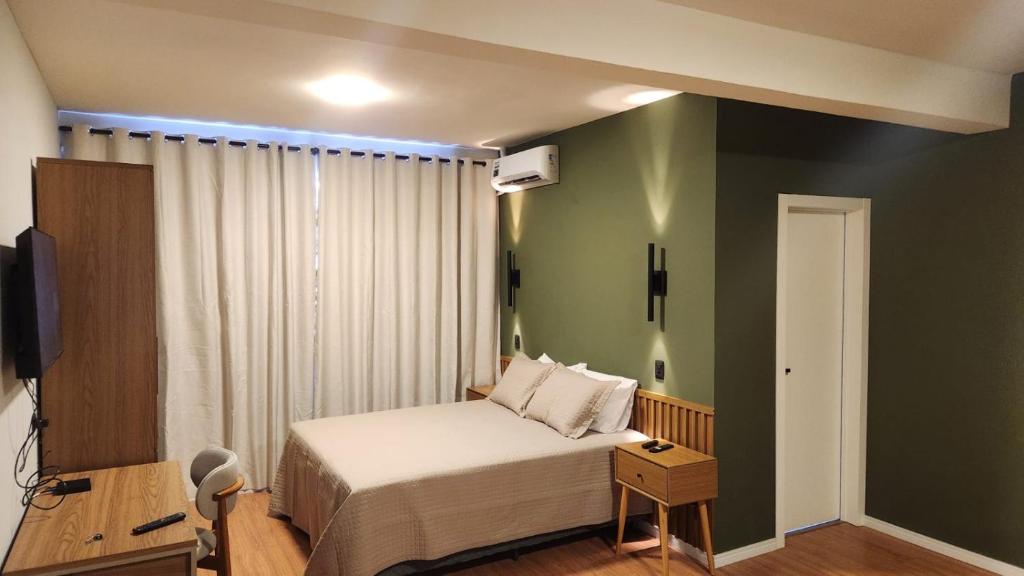 a bedroom with a bed and a green wall at Studio Cotia Próximo ao Thermas da Mata, Animalia Park e CT São Paulo in Cotia