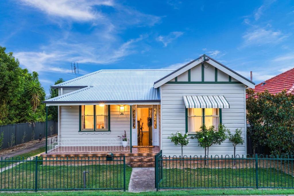 a white house with a fence in front of it at Mildas Cottage Hunter Valley in Cessnock